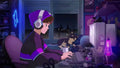 Person wearing headphones using computer in a dark room with a dog and retro music CD disk nearby